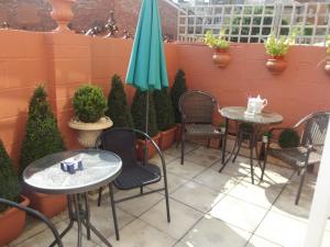 een patio met 2 tafels en stoelen en een parasol bij No24 Ventnor in Ventnor