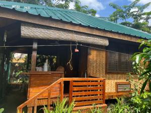 a cottage with a porch and a green roof at MALAIKA RESORT in San Vicente