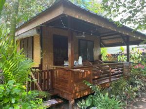 une petite maison avec un porche dans un jardin dans l'établissement MALAIKA RESORT, à Port Barton