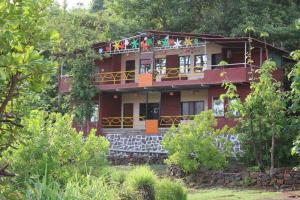 people sitting on the balcony of a red house at Couple Friendly Abode Jungle Bathtub in Kolād