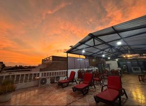 a rooftop patio with red chairs and a sunset at Hostal Gardner in Puerto Ayora