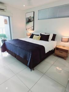 a bedroom with a large bed with a blue comforter at Skyview 2 bathroom Sub-Penthouse Harbour Views in Darwin