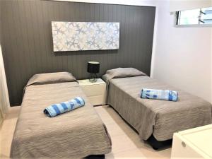 two beds in a bedroom with two pillows on them at Frangipani 206 beachfront apartment in Hamilton Island +1 photo