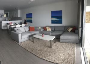 a living room with two couches and a table at Frangipani 206 beachfront apartment in Hamilton Island