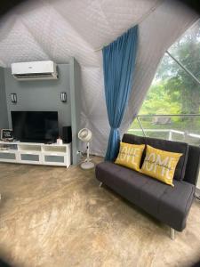 a living room with a couch and a television at Isla Riviere Dome Tent Luxury Glamping , Laguna in Salangbato