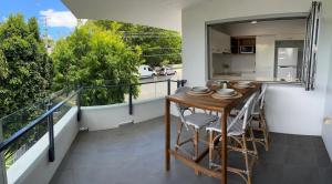 ブリスベンにあるLocation, location, location - spacious apartmentの木製のテーブルと椅子、キッチンのあるバルコニー