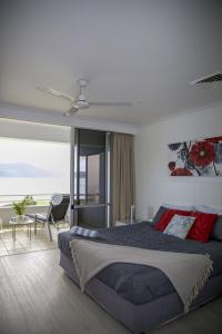 a bedroom with a large bed and a view of the ocean at Frangipani 206 beachfront apartment in Hamilton Island