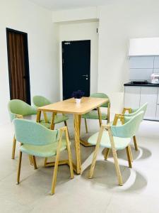 a wooden table with green chairs and a table and a table and chairs at Sleek Cottage GLEN 1 HomeStay Kuching in Kuching
