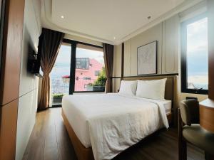 a bedroom with a white bed and a large window at Cozy Garden Boutique hotel in Khu Chi Lăng