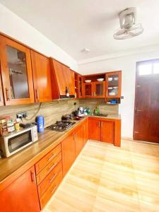 cocina grande con armarios de madera y microondas en Devon Villa Hikkaduwa, en Hikkaduwa