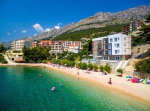 a beach with a bunch of people in the water at Apartmani Villa Borzic in Omiš