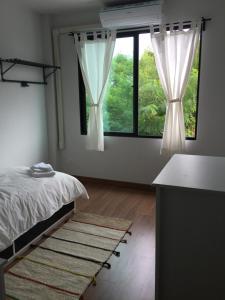 a bedroom with a bed and two large windows at 3 Bedrooms townhome, gated community KKC in Ban Si Than