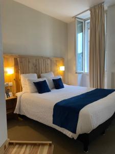 Un dormitorio con una cama grande con almohadas azules. en Logis Hôtel de France & Restaurant Pamiers, en Pamiers