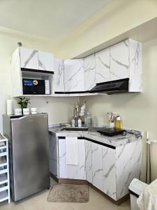 a kitchen with white cabinets and a stainless steel refrigerator at Pool view Studio with WiFi & Netflix , Avida Riala in Cebu City