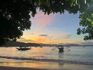 two boats in the water on a beach at sunset at MALAIKA RESORT in San Vicente