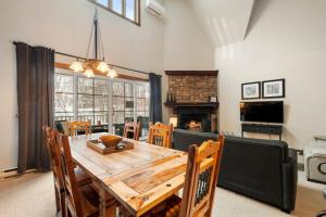 a dining room with a wooden table and a fireplace at Les Manoirs 3bdrs Near Village in Mont-Tremblant