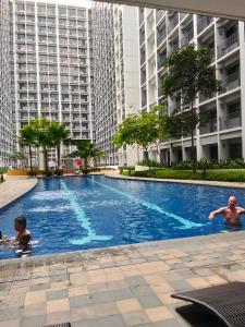 マニラにあるShore2 tower2 11th floor, unit 1122 VSV Luxury Family Suite staycation Moaの建物内のスイミングプールで泳ぐ者