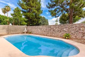 a swimming pool in front of a stone wall and trees at Upgraded Luxury 4 Bedroom Retreat with Pool & BBQ in Glendale