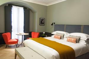 1 dormitorio con 1 cama grande con sillas naranjas en Locanda Pandenus, en Milán