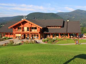 a large wooden building with mountains in the background at Green Inn Hotel in Ostravice