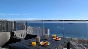 a table with two plates of food on a balcony at SUNSET WAVES sea & sky apartment in Benidorm