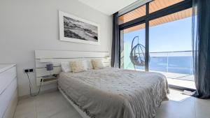 a bedroom with a bed and a large window at SUNSET WAVES sea & sky apartment in Benidorm