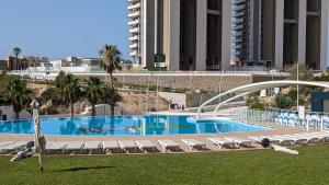 a swimming pool with lounge chairs and a building at SUNSET WAVES sea & sky apartment in Benidorm