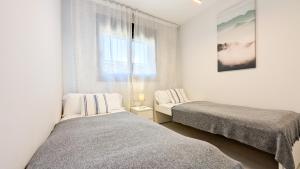 a bedroom with two beds and a window at SUNSET WAVES sea & sky apartment in Benidorm