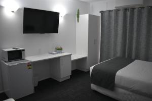 a hotel room with a bed and a desk with a tv at Riviana Motel in Deniliquin