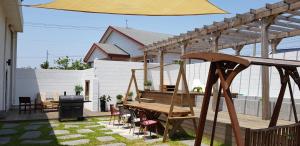 a patio with a wooden table and chairs and an umbrella at Another day in Jeju in Seogwipo