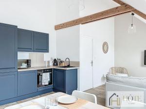 a kitchen with blue cabinets and a table at La Brise de Mer - Appt à 50m de la plage in Bray-Dunes