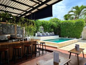 an outdoor bar with stools and a swimming pool at Lay Day Hostel Canggu in Canggu