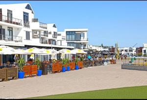 a row of tables and chairs with umbrellas at Breezy Sunny Apartment in Cape Town