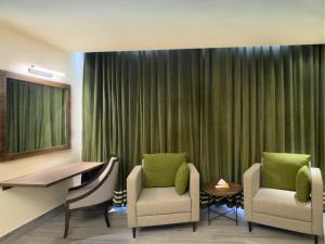a room with two chairs and a desk and a table at Hotel One Vogue Mall 35 Rawalpindi in Rawalpindi