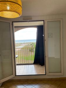 una puerta corredera de cristal con vistas a la playa en Le Palm Beach vue mer le Barcares, en Le Barcarès