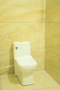a white toilet in a bathroom with a wooden wall at Cloudy Hills Homestay, Ramakkalmedu,Idukki in Ramakkalmedu