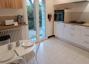 a kitchen with white cabinets and a table with chairs at Grand appartement, 2 chambres et jardin in Nîmes