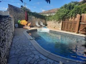 a swimming pool in a yard with a stone wall at Havre de paix en Charente Maritime avec 3 formules d hébergement sur mesure de 1 à 14 voyageurs in Gémozac