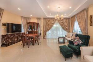 a living room with a tv and a table and chairs at Grande Pool Villa BBQ&Pool party in Bang Sare