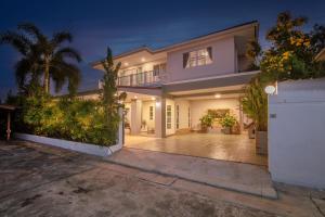 a large white house with a driveway at night at Grande Pool Villa BBQ&Pool party in Bang Sare