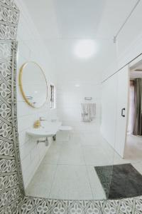 bagno bianco con lavandino e specchio di La Grace a Kempton Park