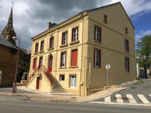 a yellow building with red doors and stairs on a street at Chez Jo in Flize