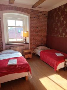 a bedroom with two beds and a brick wall at Na Plebanii in Jaszkowo