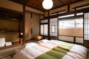 a bedroom with a bed in a room with windows at Nunoya Ryokan in Matsumoto