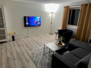 a living room with a couch and a tv on the wall at Aurora apartment Nygård in Sletta