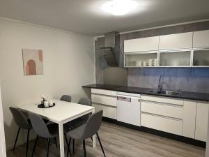 a kitchen with a table and chairs and a sink at Aurora apartment Nygård in Sletta