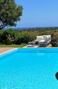 - une piscine bleue avec une table et des chaises dans l'établissement Villa con piscina e vista mare, à Tanaunella