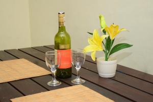 a bottle of wine and two wine glasses on a wooden table at Rosa Villa in Galle