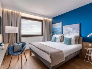 a bedroom with a large bed with a blue wall at Novotel Gdańsk Marina in Gdańsk
