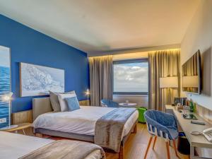 a hotel room with two beds and a desk at Novotel Gdańsk Marina in Gdańsk